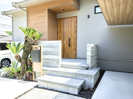 ソテツがアクセントになっているシンプルで機能的なファサードと玄関アプローチ