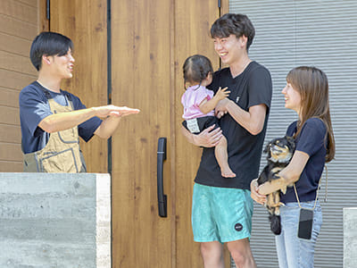 施工した住宅のファサードの前でご家族とお話しするエデンホームのスタッフ